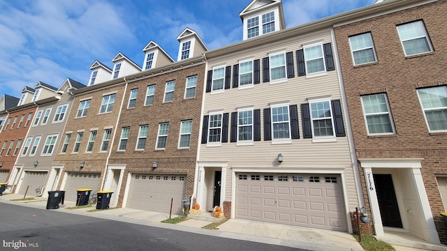 townhome / multi-family property with a garage and brick siding