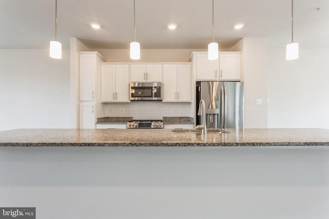 kitchen with stainless steel appliances, pendant lighting, and white cabinetry