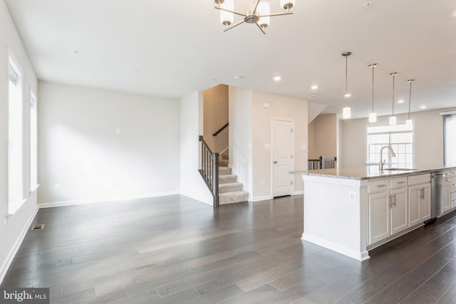 kitchen featuring a sink, white cabinetry, open floor plan, light stone countertops, and an island with sink