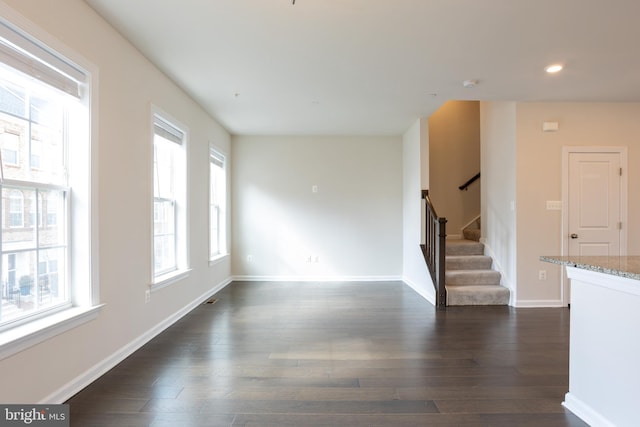 empty room featuring recessed lighting, dark wood-style flooring, stairway, and baseboards