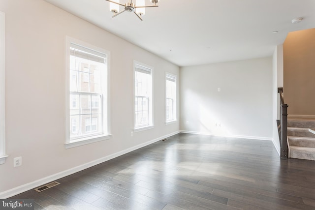 spare room with dark wood-style flooring, visible vents, an inviting chandelier, baseboards, and stairs