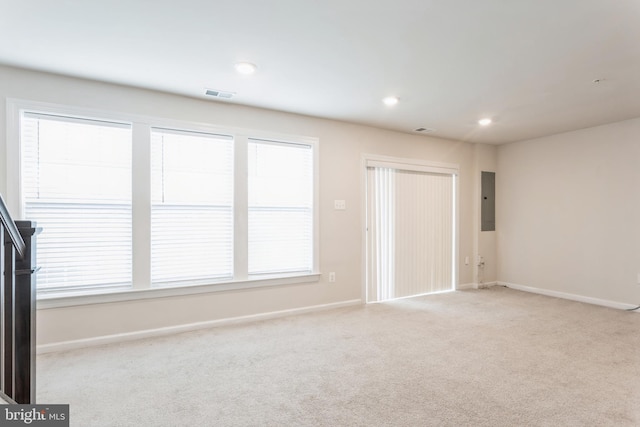 spare room with electric panel, visible vents, baseboards, light colored carpet, and recessed lighting