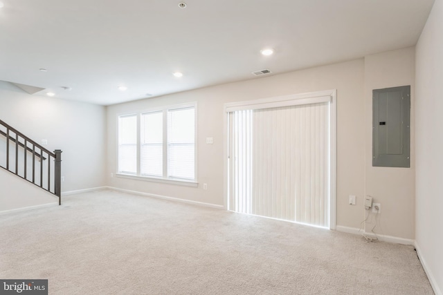 unfurnished living room with recessed lighting, visible vents, light carpet, electric panel, and stairs