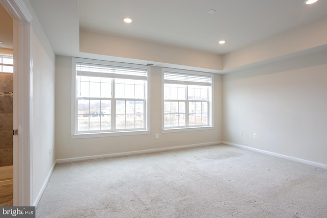 spare room with baseboards, recessed lighting, and light colored carpet