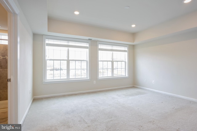 unfurnished room featuring baseboards, a wealth of natural light, and light colored carpet