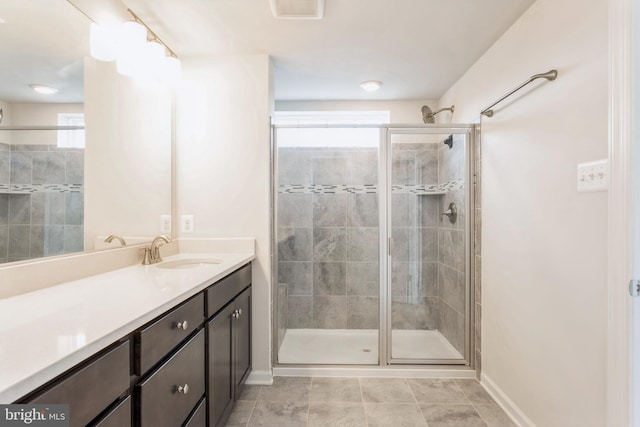 bathroom with baseboards, visible vents, vanity, and a shower stall