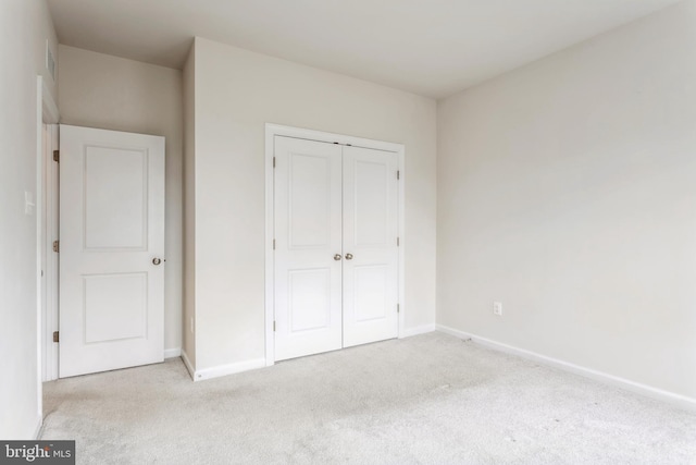 unfurnished bedroom featuring a closet, light colored carpet, and baseboards