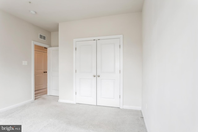 unfurnished bedroom with light carpet, a closet, visible vents, and baseboards