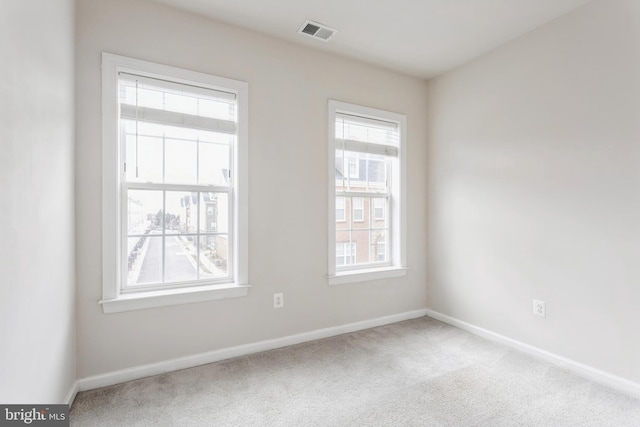 carpeted empty room featuring visible vents and baseboards