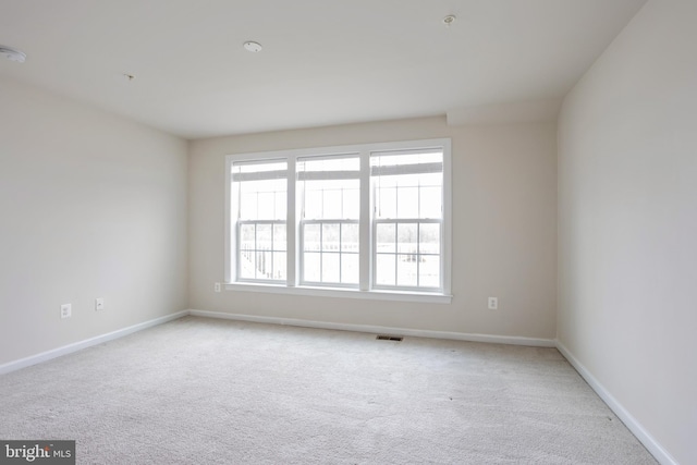 spare room featuring light carpet, baseboards, and visible vents