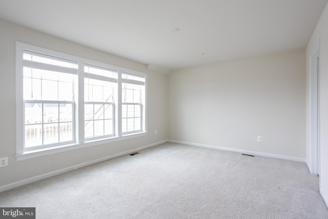 unfurnished room with light colored carpet, visible vents, and baseboards