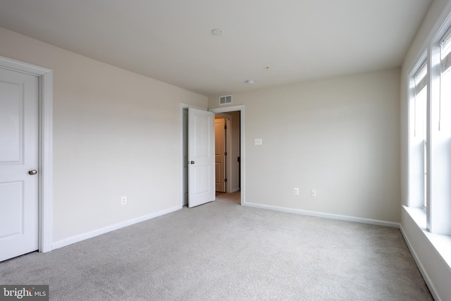 empty room with light colored carpet, visible vents, and baseboards