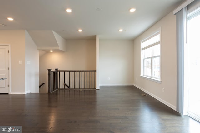 spare room featuring baseboards, dark wood-type flooring, and recessed lighting