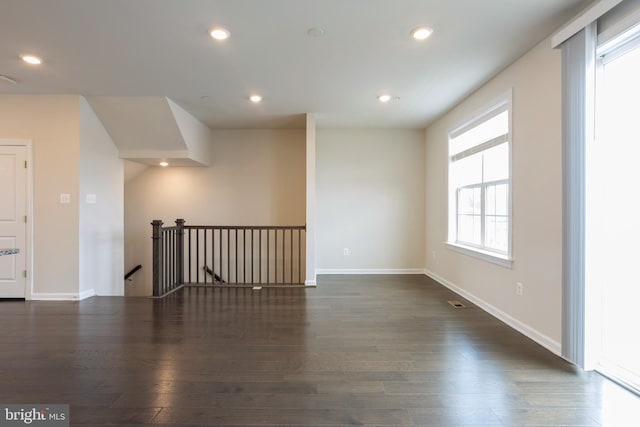 spare room with dark wood-type flooring, recessed lighting, and baseboards