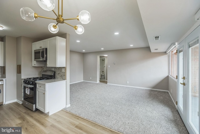 kitchen featuring white cabinetry, appliances with stainless steel finishes, light wood-type flooring, decorative backsplash, and an inviting chandelier