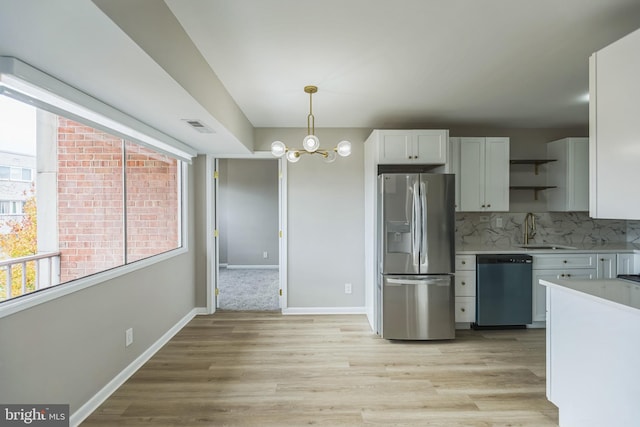 kitchen featuring stainless steel appliances, white cabinetry, sink, tasteful backsplash, and light hardwood / wood-style flooring