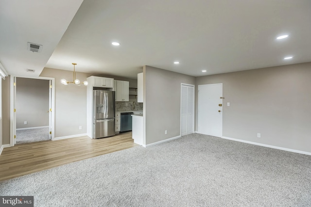 unfurnished living room featuring a notable chandelier and light hardwood / wood-style floors