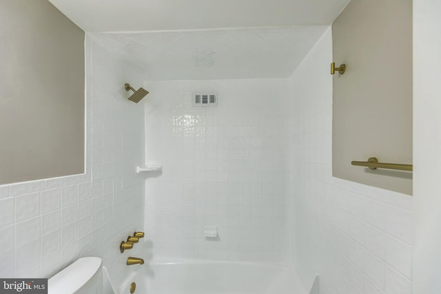 bathroom with tiled shower / bath, toilet, and tile walls