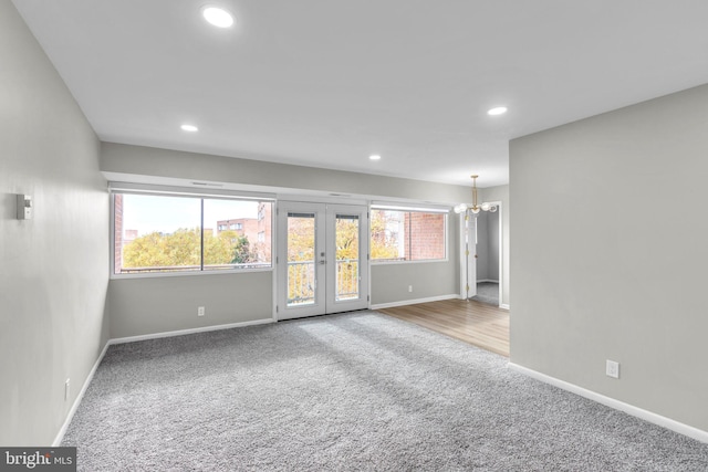 carpeted empty room with french doors and an inviting chandelier