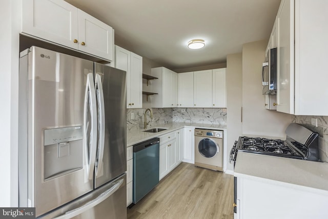 kitchen with white cabinets, appliances with stainless steel finishes, sink, and washer / dryer