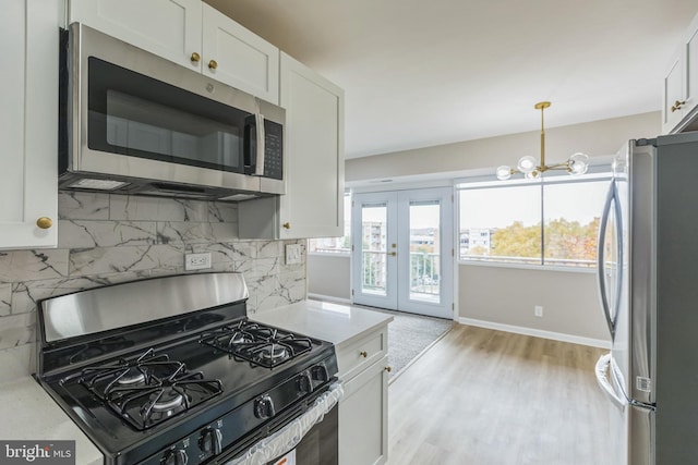 kitchen with white cabinets, decorative backsplash, stainless steel appliances, and light hardwood / wood-style floors