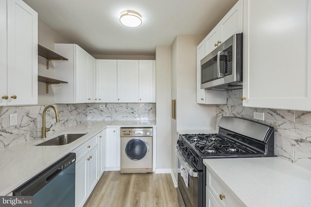 kitchen featuring white cabinetry, sink, appliances with stainless steel finishes, washer / dryer, and light hardwood / wood-style flooring