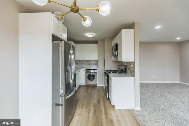 kitchen featuring light wood-type flooring, white cabinets, washer / dryer, and stainless steel appliances