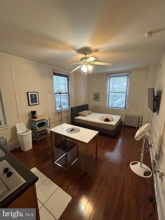 bedroom with ceiling fan, radiator heating unit, and dark hardwood / wood-style flooring