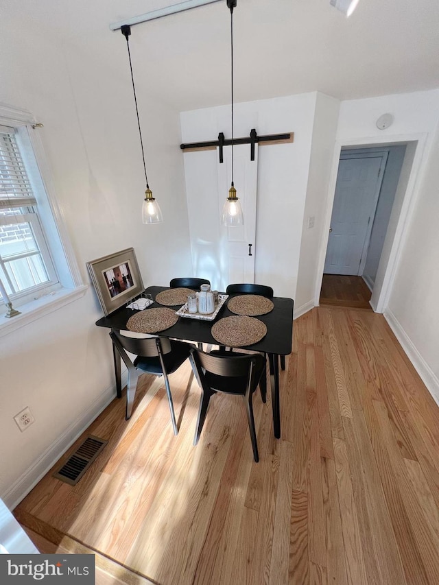 dining space with a barn door and light wood-type flooring