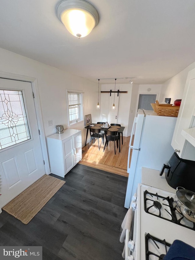 kitchen featuring dark wood-type flooring, white gas stove, and white cabinets