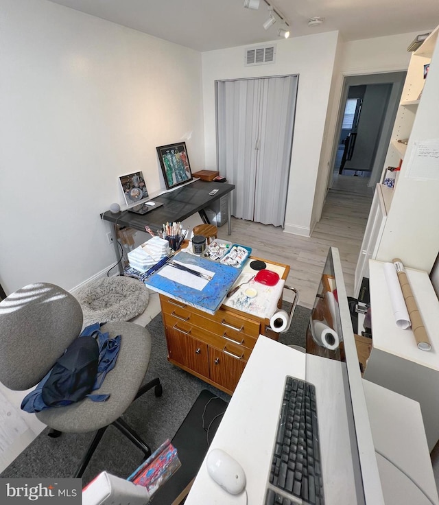 office with track lighting and light hardwood / wood-style floors