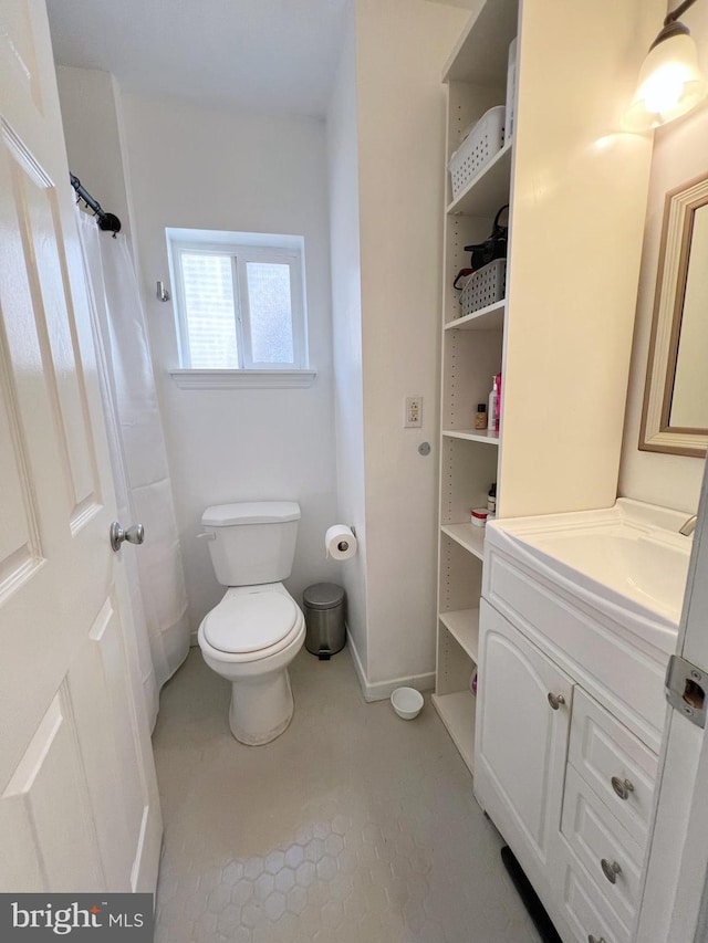 bathroom with toilet, vanity, and tile patterned floors