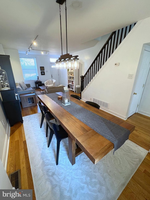 dining area with hardwood / wood-style floors and track lighting