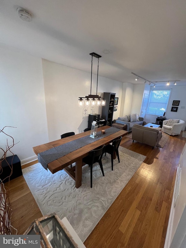 dining room with hardwood / wood-style floors, rail lighting, and an inviting chandelier