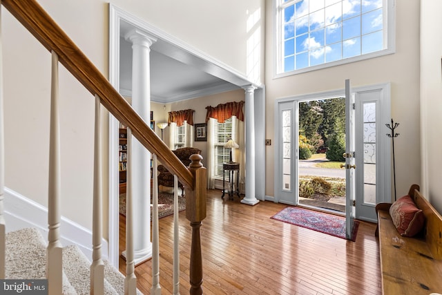 foyer with ornamental molding, hardwood / wood-style flooring, a high ceiling, and ornate columns