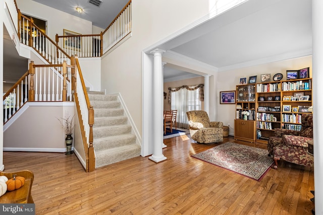 interior space featuring light hardwood / wood-style flooring, crown molding, and decorative columns