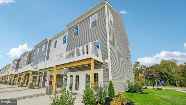 rear view of property with french doors, a lawn, and cooling unit