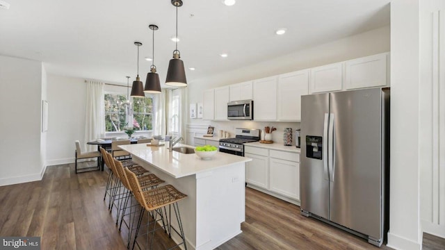 kitchen featuring a center island with sink, white cabinets, stainless steel appliances, and dark hardwood / wood-style floors