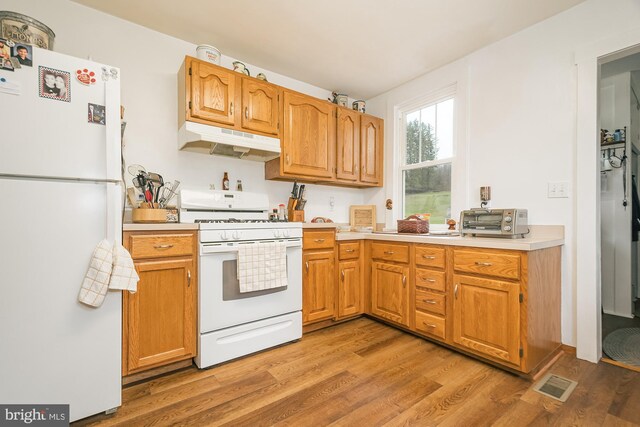 117 Accident Bittinger Rd, Accident, MD 21520 - kitchen with white appliances, under cabinet range hood, light countertops, light wood-style floors, and brown cabinetry