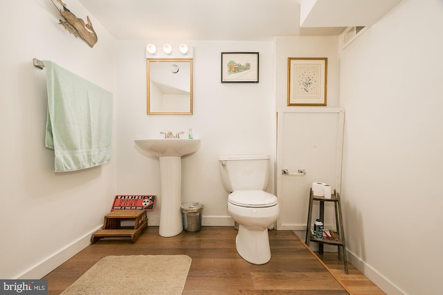 bathroom featuring toilet, sink, and wood-type flooring