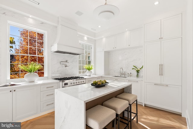 kitchen featuring white cabinets, sink, light parquet floors, and custom exhaust hood