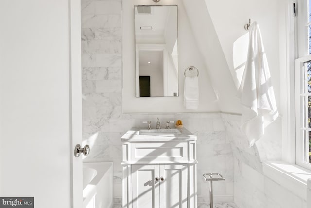 bathroom with a bathing tub, vanity, and tile walls