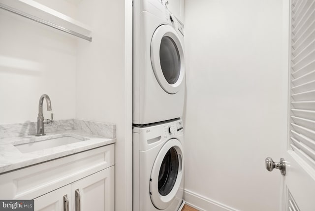 washroom with sink, cabinets, and stacked washer and clothes dryer