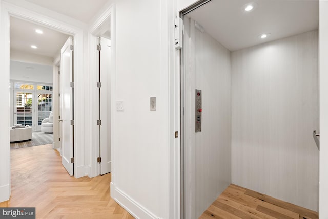 hallway with elevator and light parquet floors