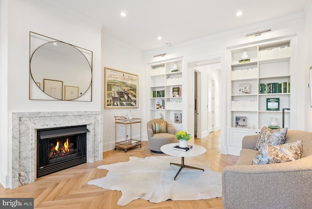 living area featuring built in features, crown molding, parquet floors, and a fireplace