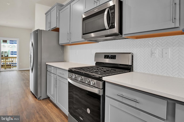 kitchen with stainless steel appliances, decorative backsplash, light hardwood / wood-style flooring, and gray cabinets