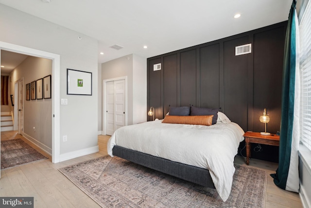 bedroom featuring a closet, multiple windows, and light hardwood / wood-style flooring