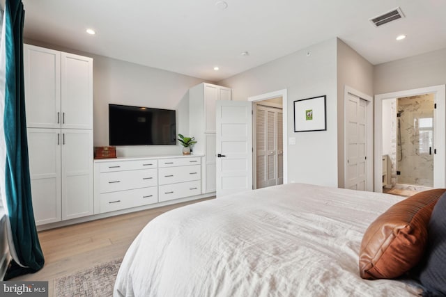 bedroom with light hardwood / wood-style flooring, two closets, and ensuite bathroom