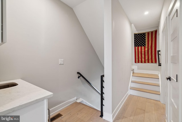 staircase with vaulted ceiling and hardwood / wood-style floors