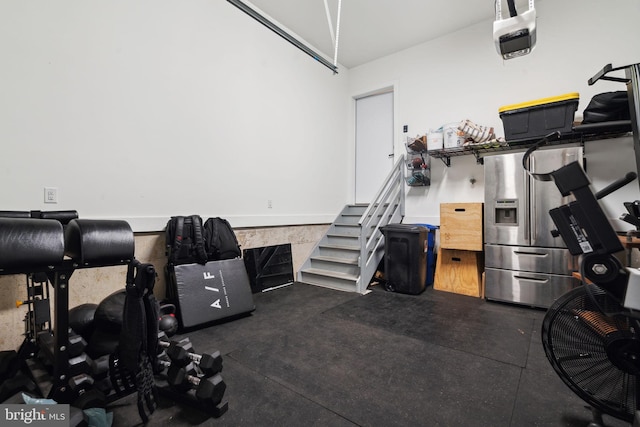 garage with a garage door opener and stainless steel refrigerator with ice dispenser